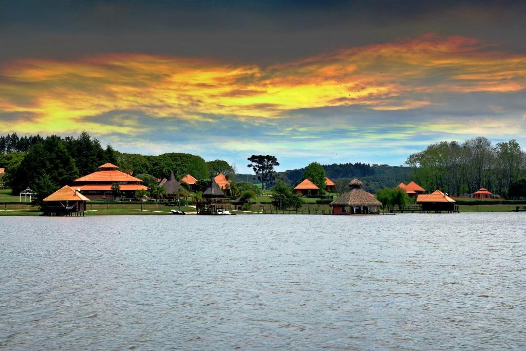 een groep hutten aan de oever van een waterlichaam bij Virá Charme Resort in Fernandes Pinheiro