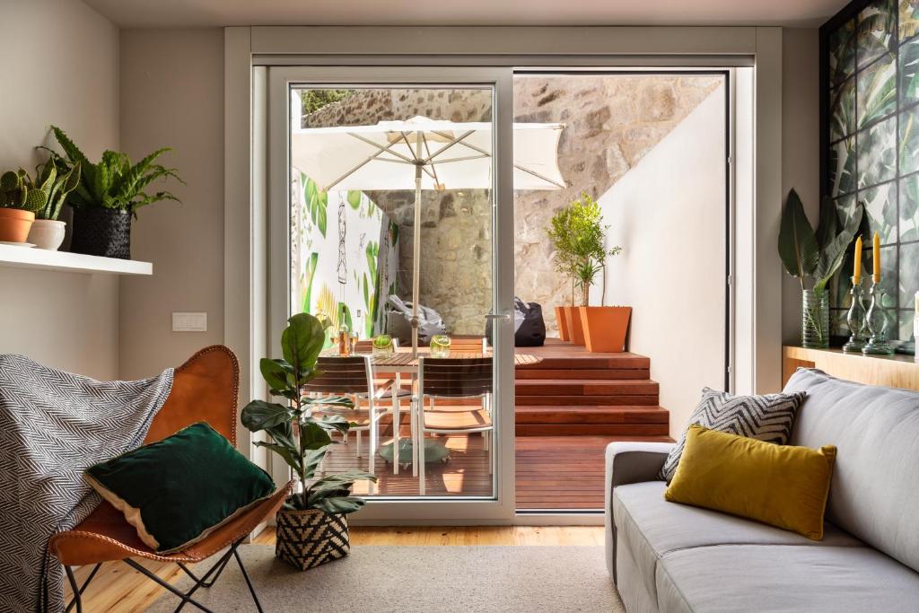 ein Wohnzimmer mit einem Sofa und einem Tisch mit einem Sonnenschirm in der Unterkunft Janika's Patio in Porto