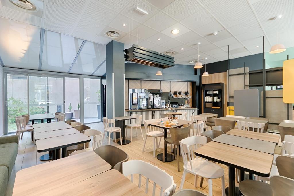 マルセイユにあるB&B HOTEL Marseille Centre La Jolietteの木製テーブルと白い椅子が備わるレストラン