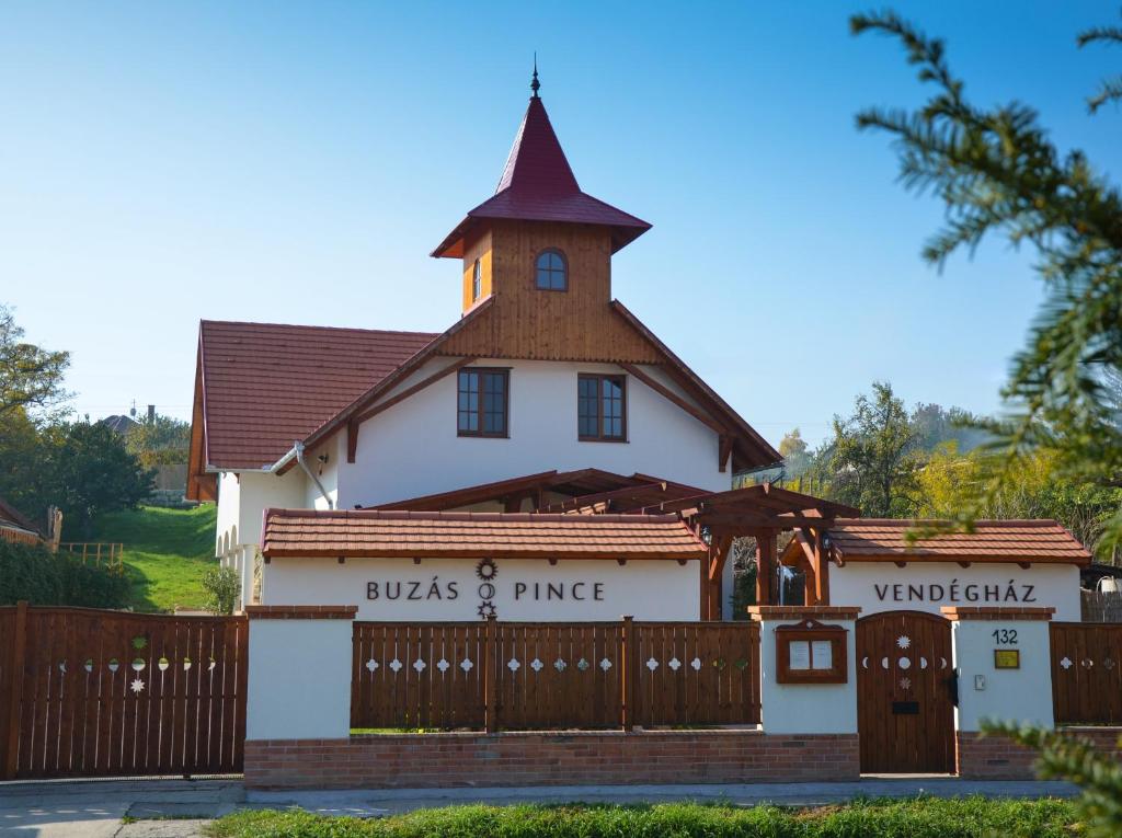 a church with a fence in front of a building at Buzás Pince Vendégház in Ecséd