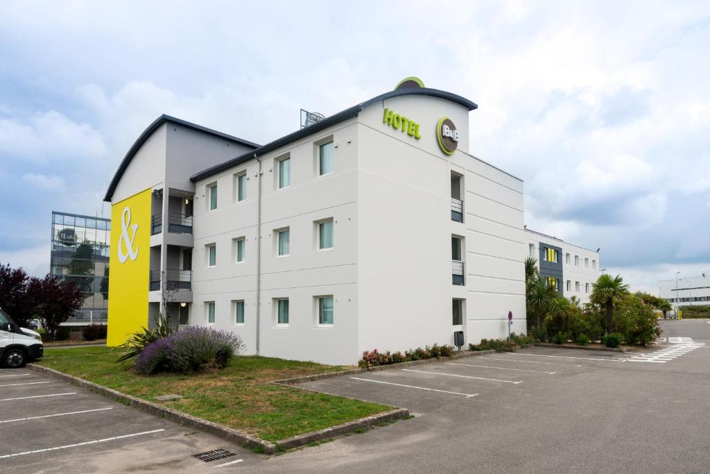 ein weißes Gebäude mit einer Uhr auf der Seite in der Unterkunft B&B HOTEL Nantes Aéroport in Bouguenais