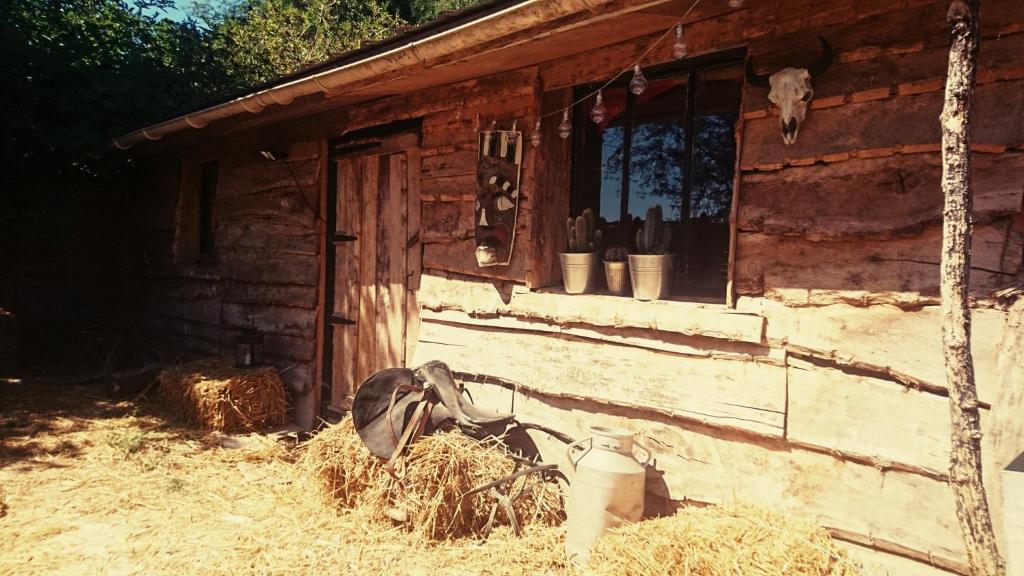 a barn with a pile of hay next to a house at La Cabane Aux Loups in Crépy-en-Valois