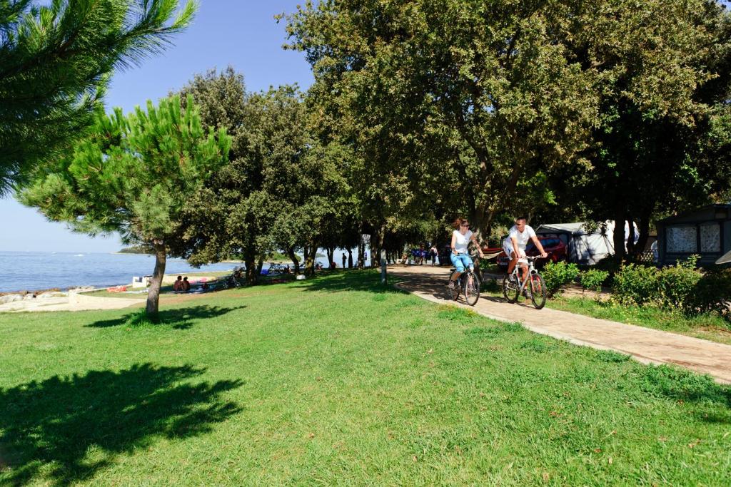 two people riding bikes on a path near the beach at Maistra Camping Valkanela Mobile homes in Funtana