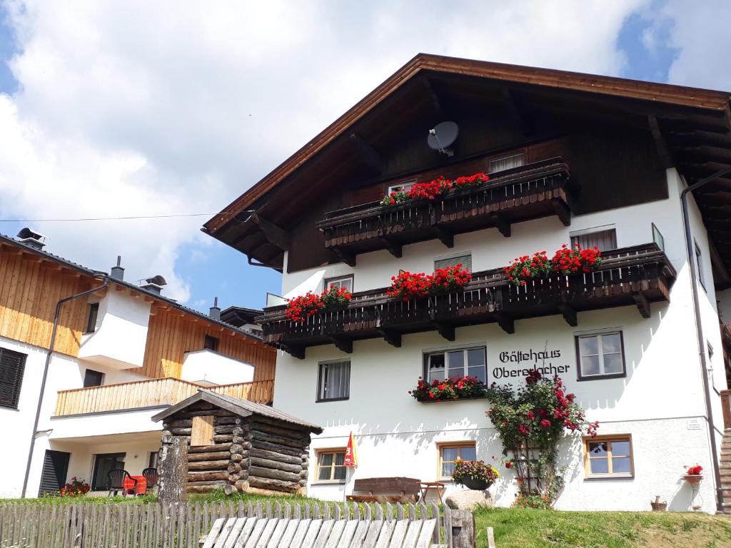 a white building with red flowers on the balconies at Gästehaus Obererlacher in Obertilliach