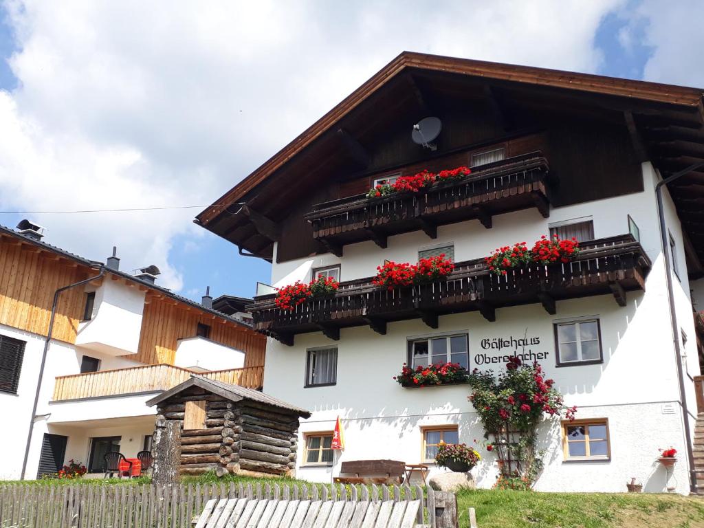 Un edificio blanco con flores rojas en los balcones. en Gästehaus Obererlacher, en Obertilliach