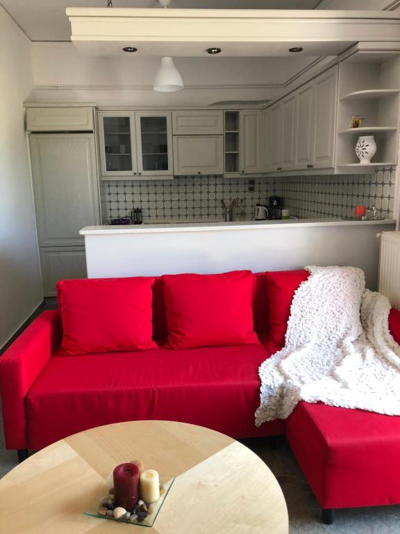 um sofá vermelho numa cozinha com uma mesa em Cozy City Apt em Heraclião