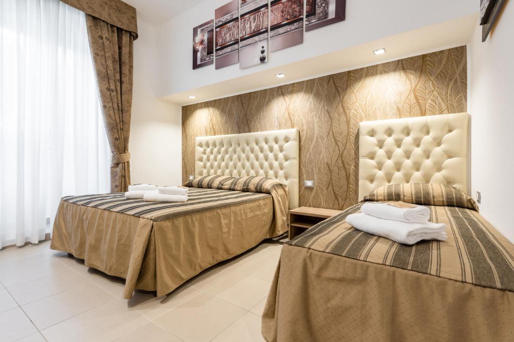 ローマにあるBrancaccio Suite 43のカーテン付きのホテルルーム内のベッド2台