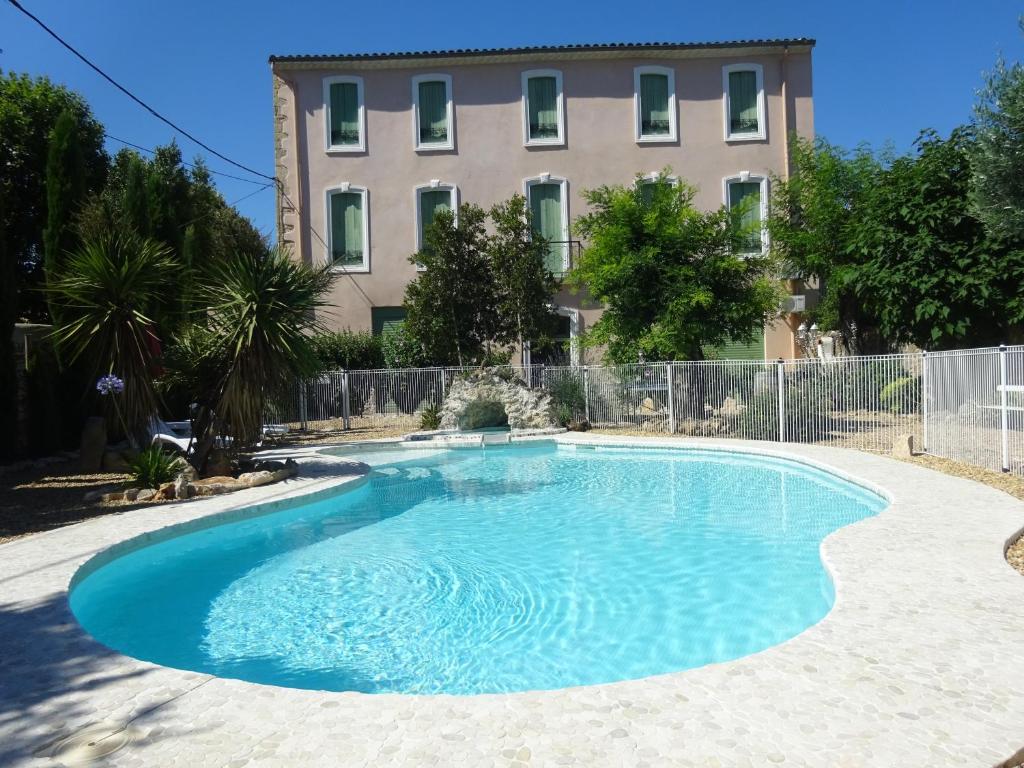 einem großen blauen Pool vor einem Gebäude in der Unterkunft Gîtes "tout au sud de la France" in Pomérols