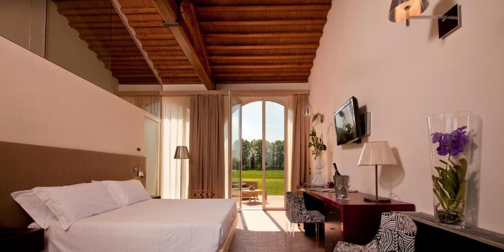 a bedroom with a bed and a desk and a window at Locanda Sant'Agata in San Giuliano Terme