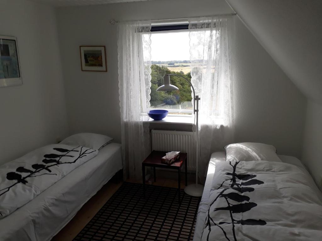 two beds in a small room with a window at Rosenhuset in Haderslev