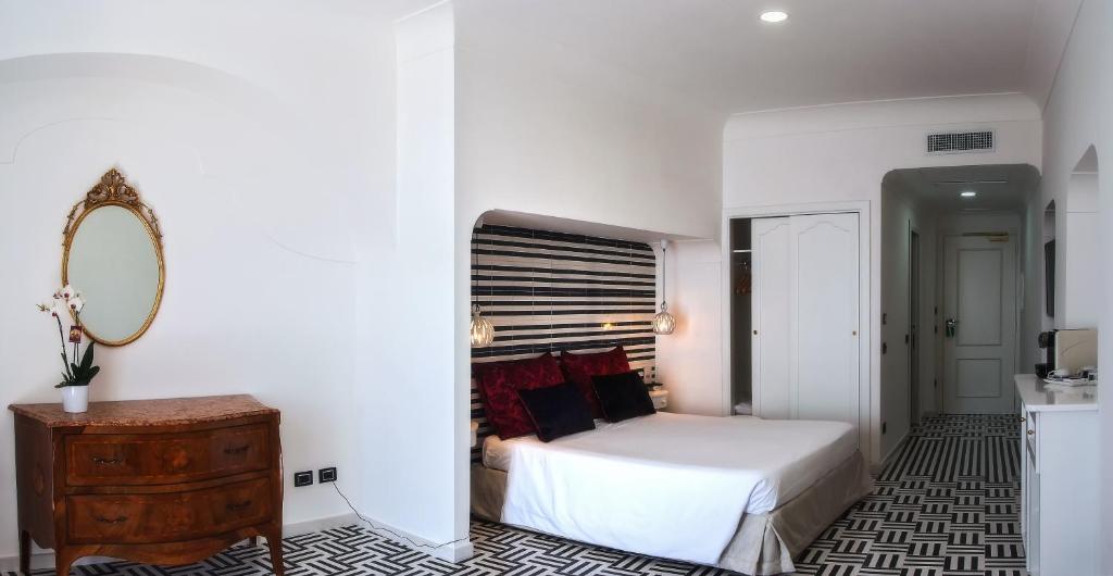 a white bedroom with a bed and a mirror at Hotel Montemare in Positano