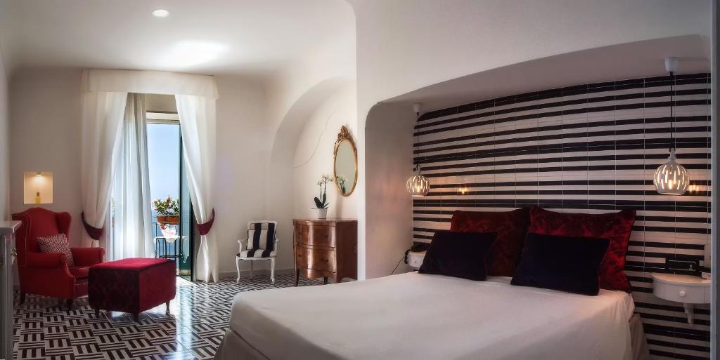 a bedroom with a large bed and a red chair at Hotel Montemare in Positano
