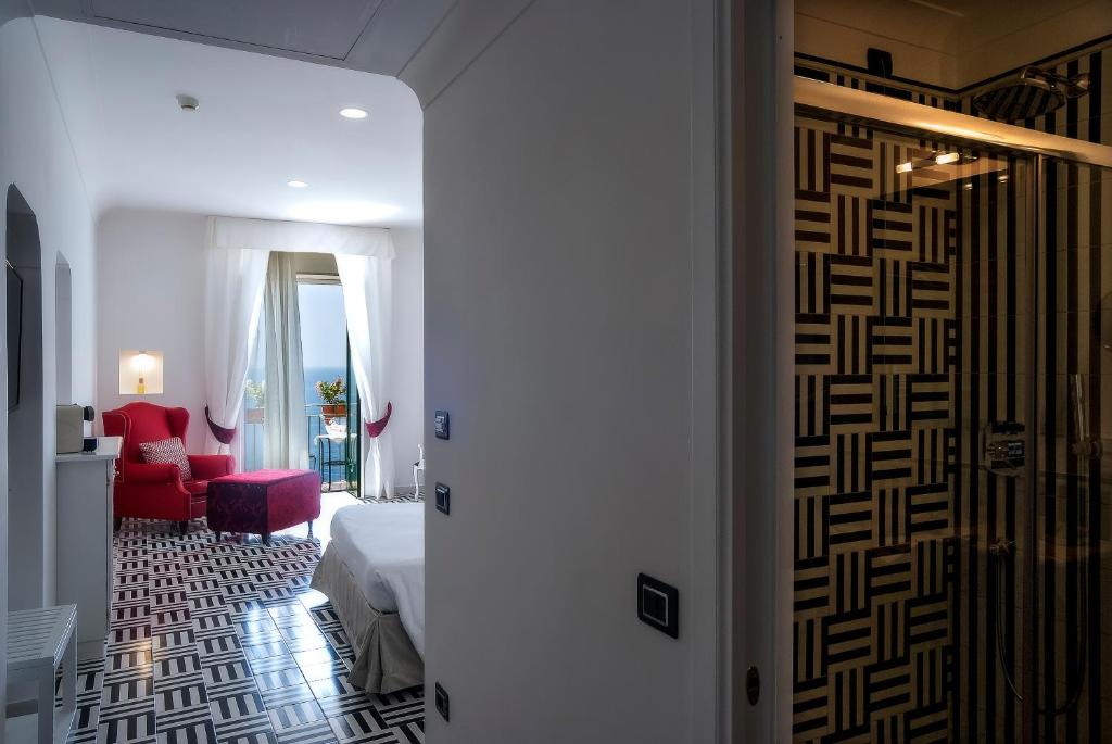 a hallway with a room with a bed and a red chair at Hotel Montemare in Positano