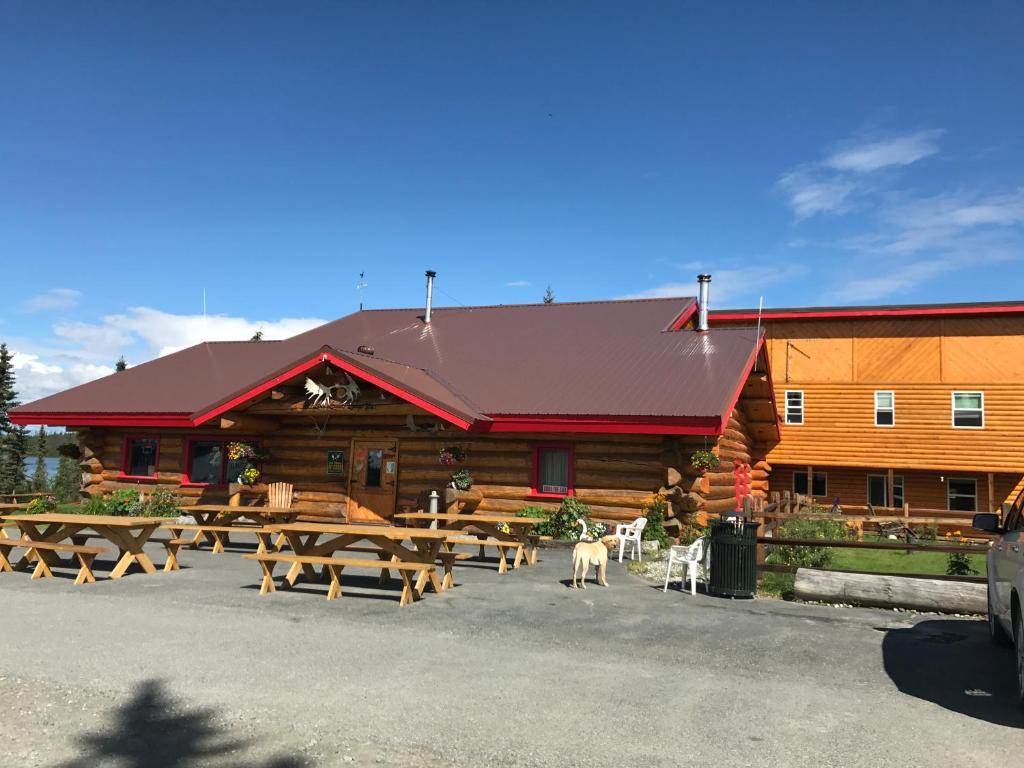 une cabane en rondins avec des tables de pique-nique devant elle dans l'établissement Lake Louise Lodge, Alaska, à Glennallen