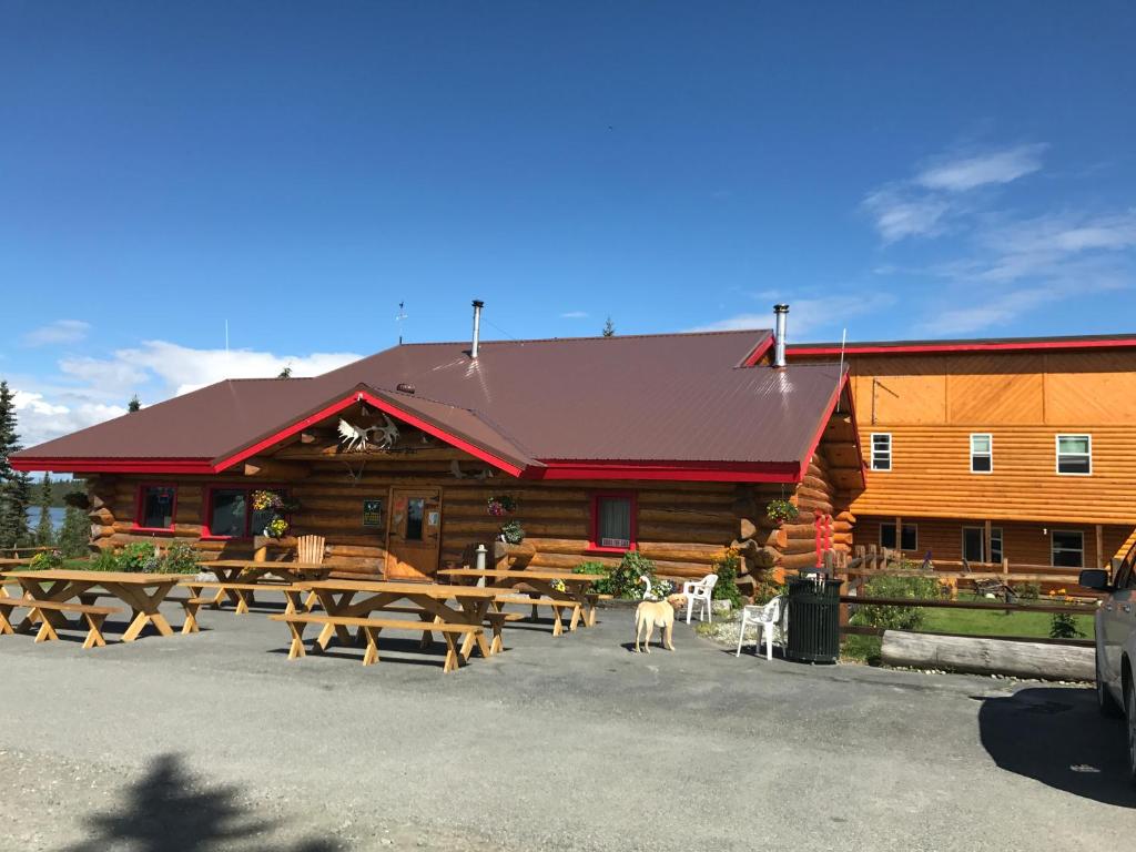 a log cabin with picnic tables in front of it at Lake Louise Lodge, Alaska in Glennallen