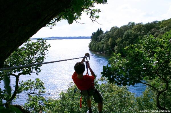 a man is hanging on a rope over a river at Le cocon des lacs in Boussu-lez-Walcourt