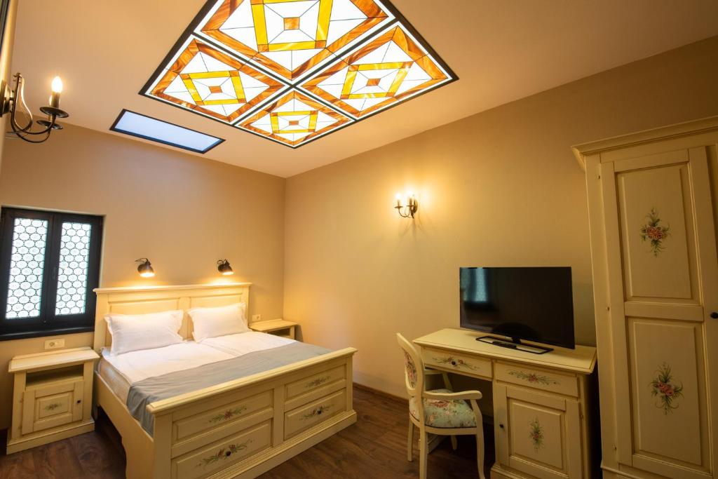 um quarto com uma cama, uma televisão e uma janela em HOTEL BOUTIQUE CASA CHITIC -HOTEL AND RESTAURANT Str Johann Gott nr7 em Braşov