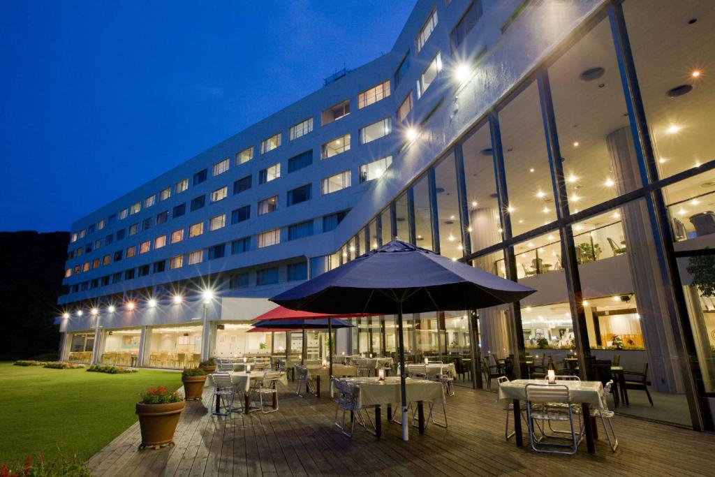 an outdoor patio with tables and an umbrella in front of a building at Hotel Izukyu in Shimoda
