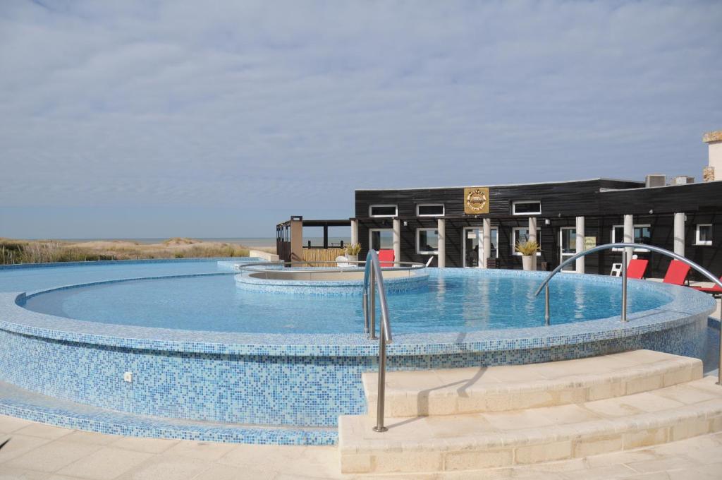 une grande piscine en face d'un bâtiment dans l'établissement Linda Bay Beach & Resort Spa, à Mar de las Pampas