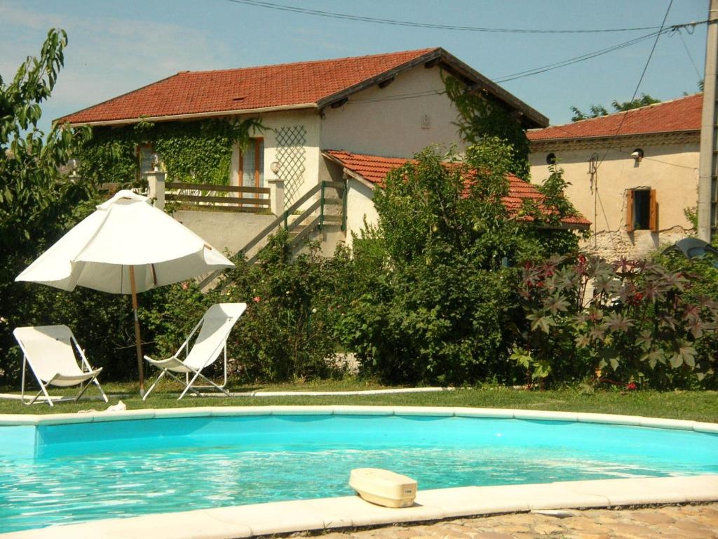 a swimming pool with two chairs and an umbrella at Chambres d'hôtes- Le Pré aux Ânes in Albon