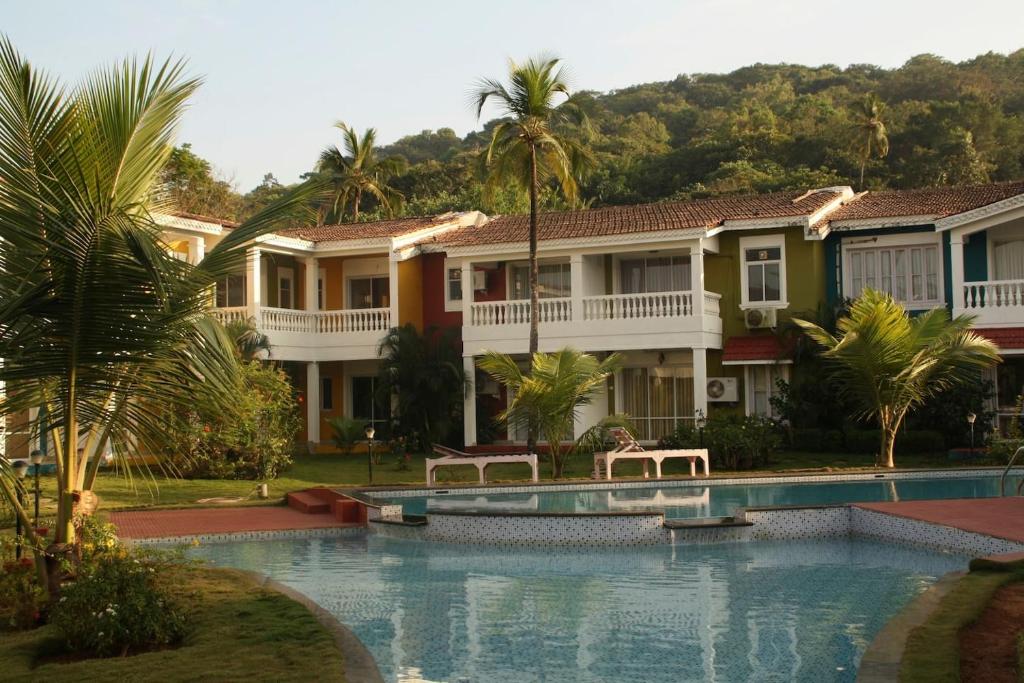 a house with a swimming pool and palm trees at Riverside Villa at Siolim in Siolim