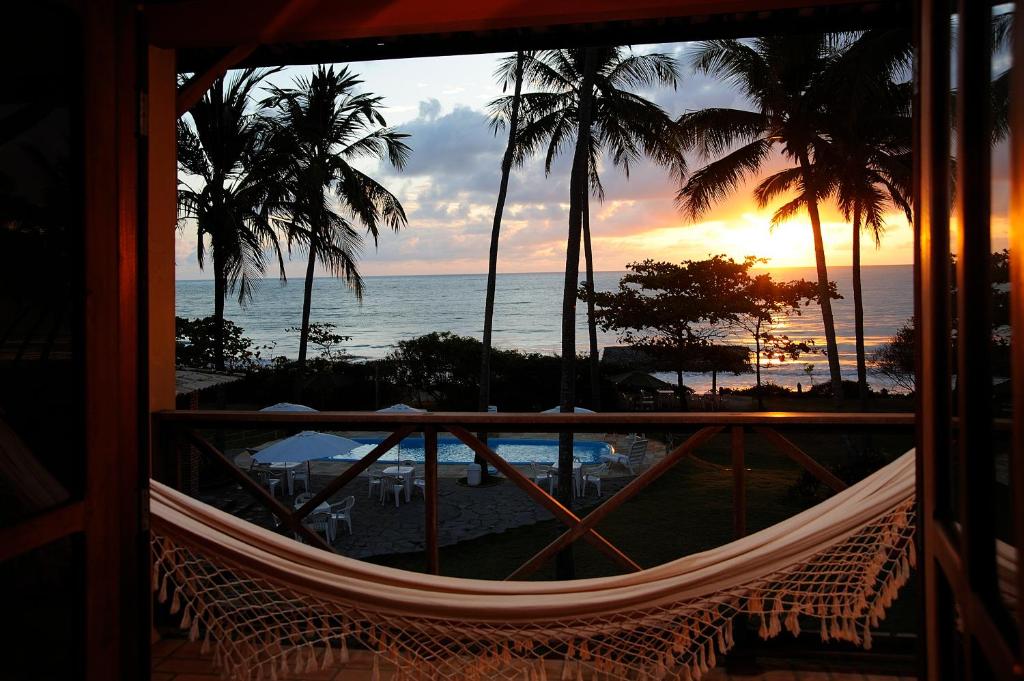 uma rede de descanso num quarto com vista para o oceano em Igarakuê Hotel Pousada em Japaratinga