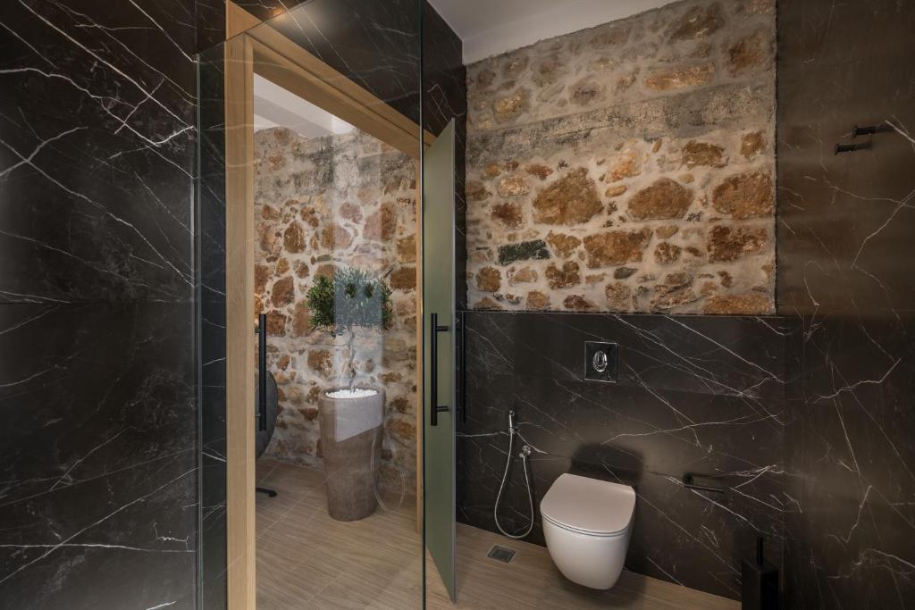 łazienka z toaletą i kamienną ścianą w obiekcie Agave Suites w Chanii