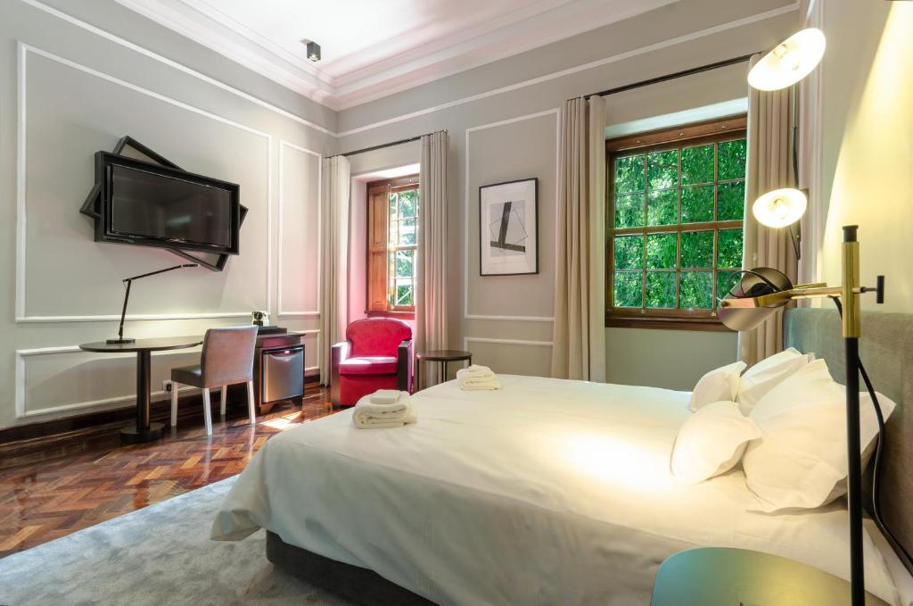 a bedroom with a bed and a desk and a tv at Le Jardin Lisbon in Lisbon