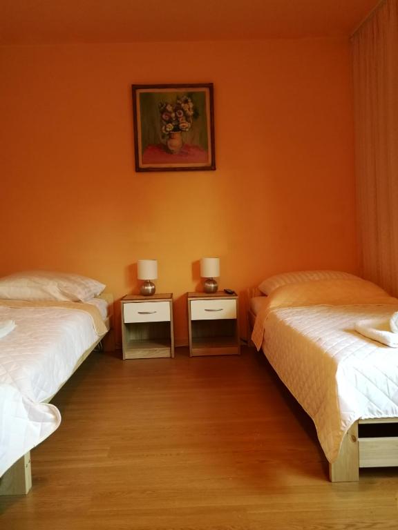 2 łóżka w pokoju z pomarańczowymi ścianami w obiekcie Noclegi u Mai w Olsztynie