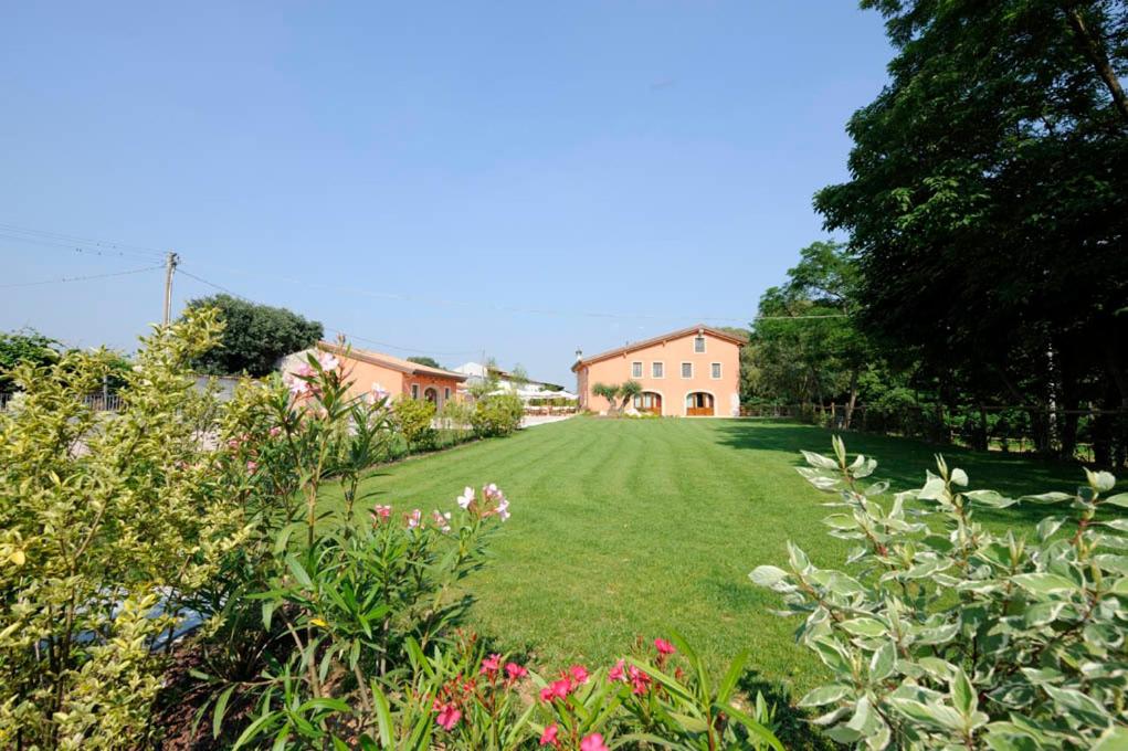 un ampio cortile erboso con una casa sullo sfondo di Agriturismo Corte Morandini a Valeggio sul Mincio