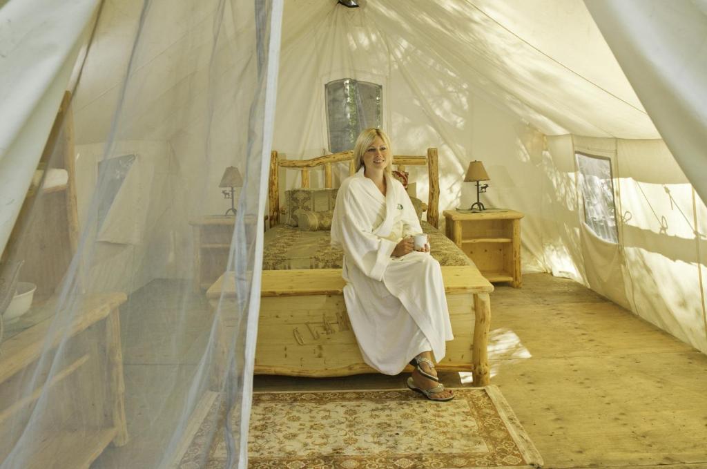 a woman sitting on a bed in a tent at WildExodus Outdoors in Timmins