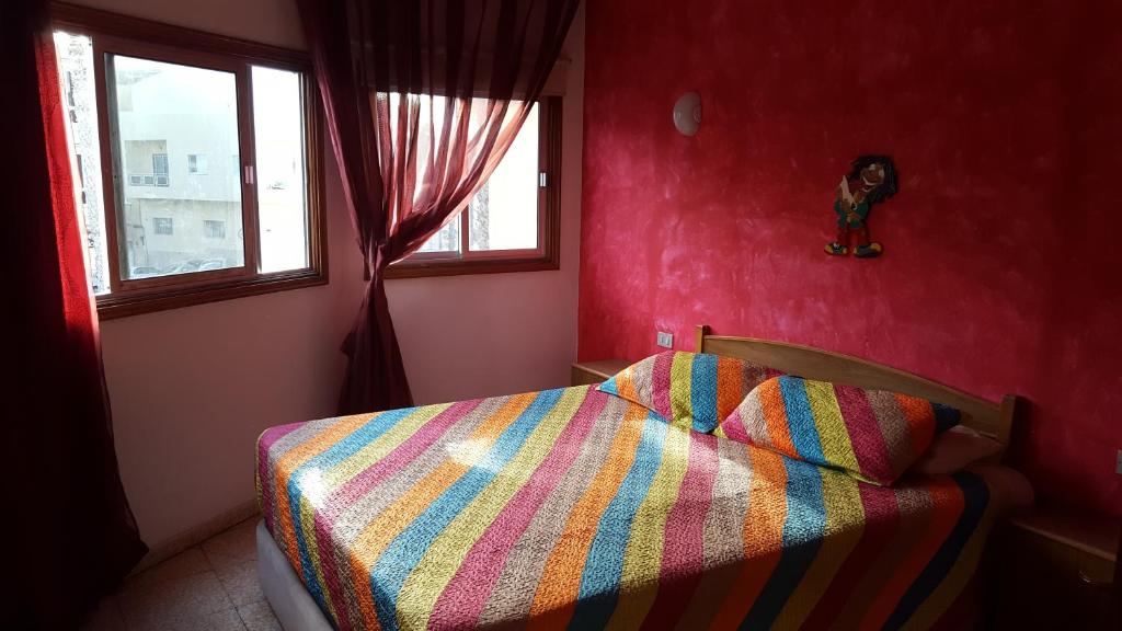 a bedroom with a bed with a colorful comforter and a window at Habitaciones Javi Los Abrigos in Golf del Sur