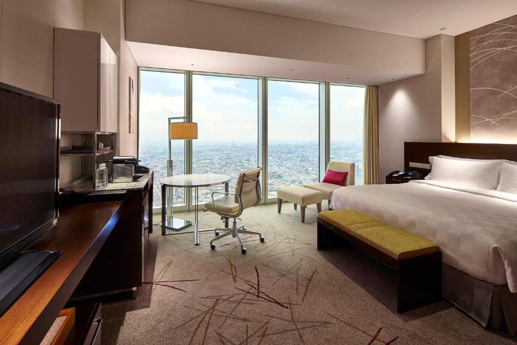 a hotel room with a bed and a table and chairs at Osaka Marriott Miyako Hotel in Osaka