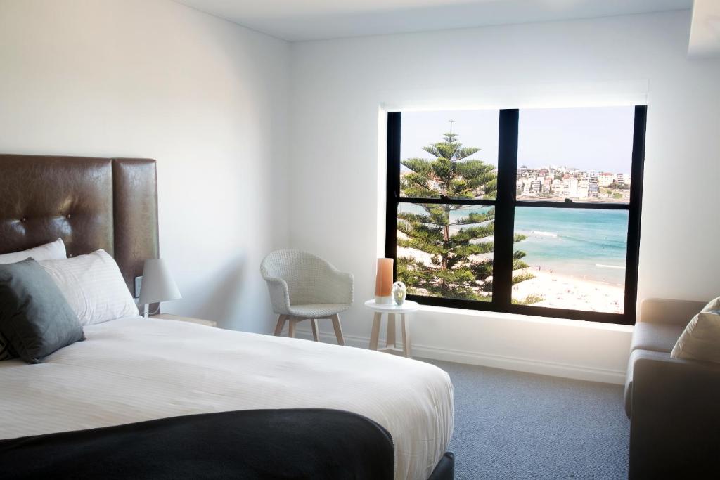 a bedroom with a bed and a view of the beach at Bondi 38 Serviced Apartments in Sydney