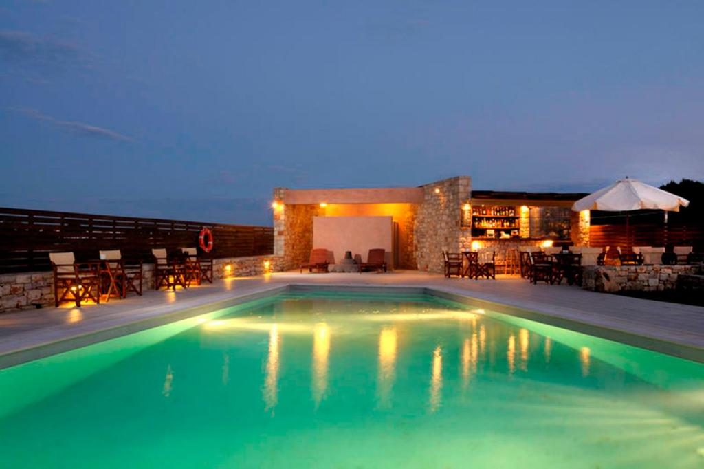 a swimming pool at night with tables and chairs at Petradi in Livadi