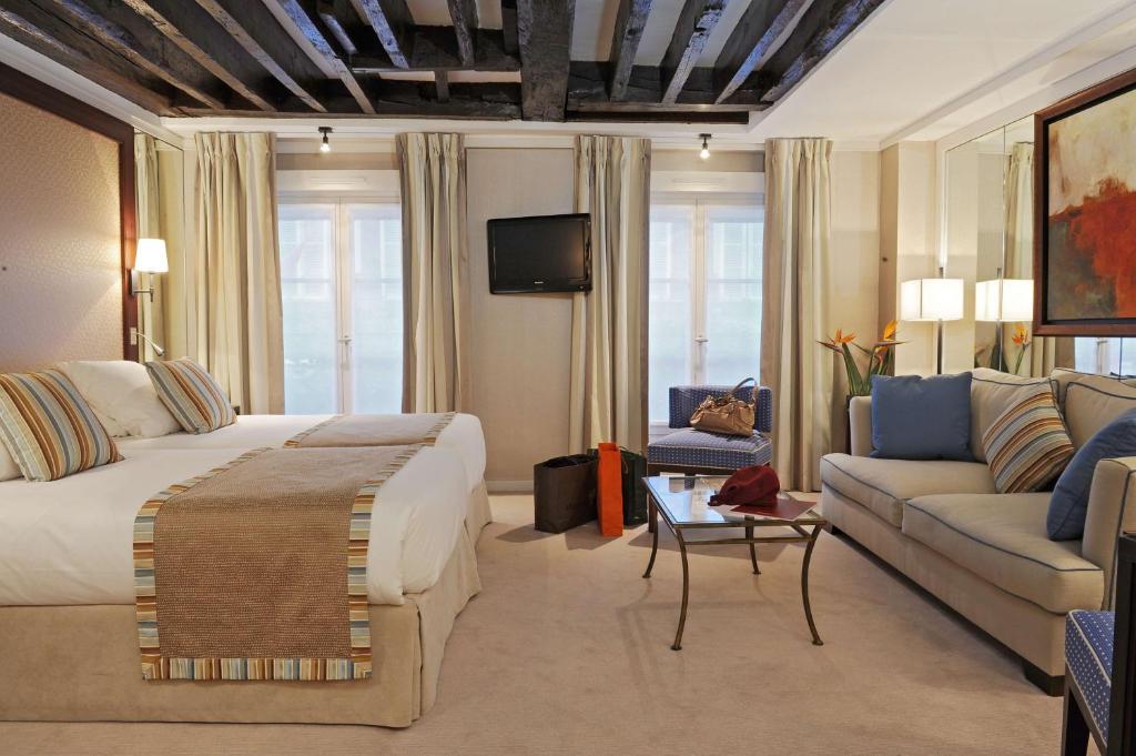 ein Hotelzimmer mit einem Bett und einem Sofa in der Unterkunft Folkestone Opéra in Paris