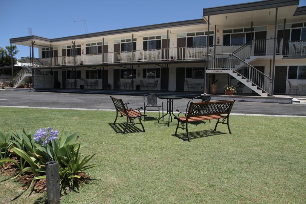 3 sedie e un tavolo di fronte a un edificio di Waterview Motel Maclean a Maclean