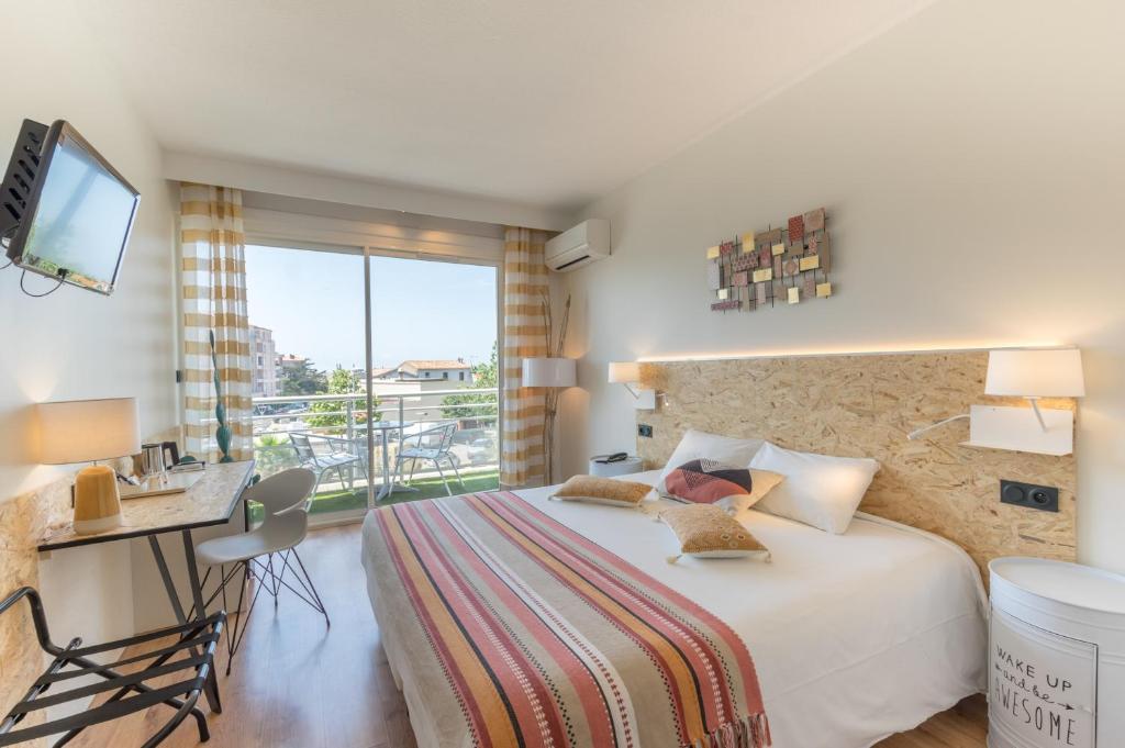 una camera con letto, scrivania e TV di Cit'Hotel Imperial a Sète