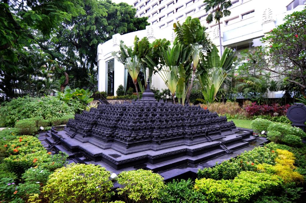 a garden with a fountain in the middle of a building at Hotel Borobudur Jakarta in Jakarta