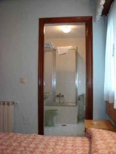 a bedroom with a bathroom with a shower and a bed at Hotel Auto-Bar in Grado