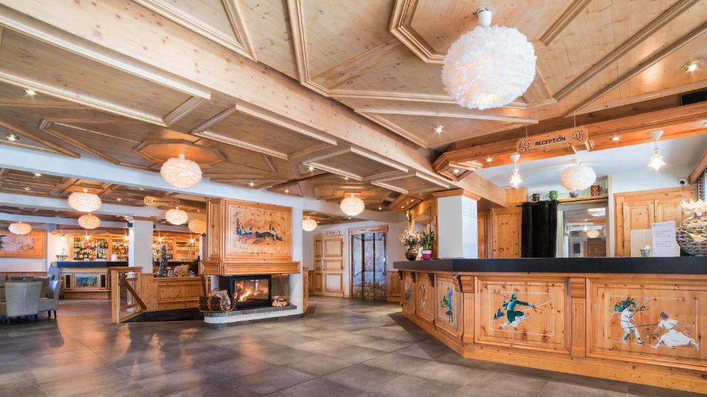 a large room with a fireplace and wooden ceilings at Hotel le Petit Dru in Morzine