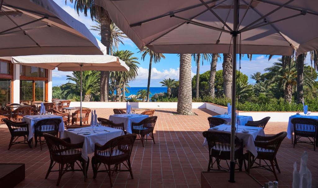 a restaurant with tables and chairs and umbrellas at Hotel Porto Santo & Spa in Porto Santo