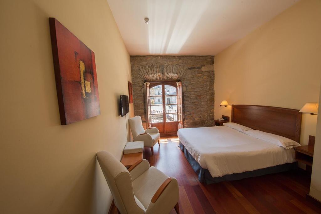 a hotel room with a bed and two chairs at Hotel Aroi Bierzo Plaza in Ponferrada