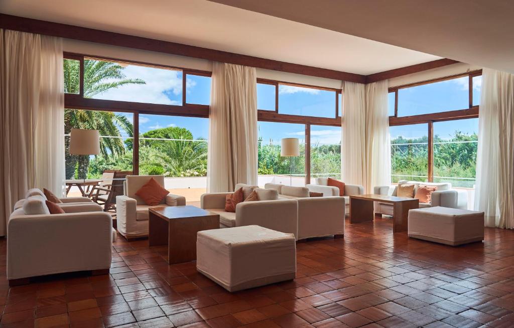 a living room with white furniture and large windows at Hotel Porto Santo & Spa in Porto Santo