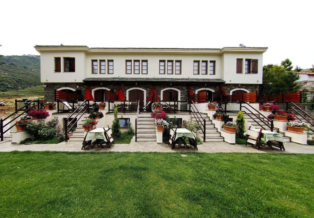 une grande maison avec des tables et des chaises en face de celle-ci dans l'établissement Smaragdi Luxury Apartments, à Skala Sotiros