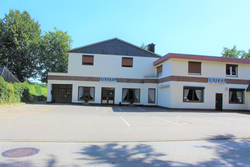 a large white building with a parking lot at Hotel Alsterquelle in Henstedt-Ulzburg