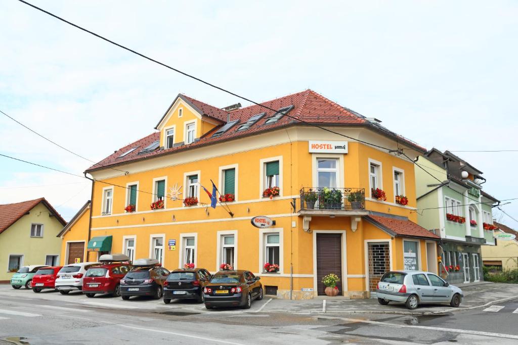 普圖伊的住宿－Hostel Sonce，一座黄色的建筑,前面有汽车停放