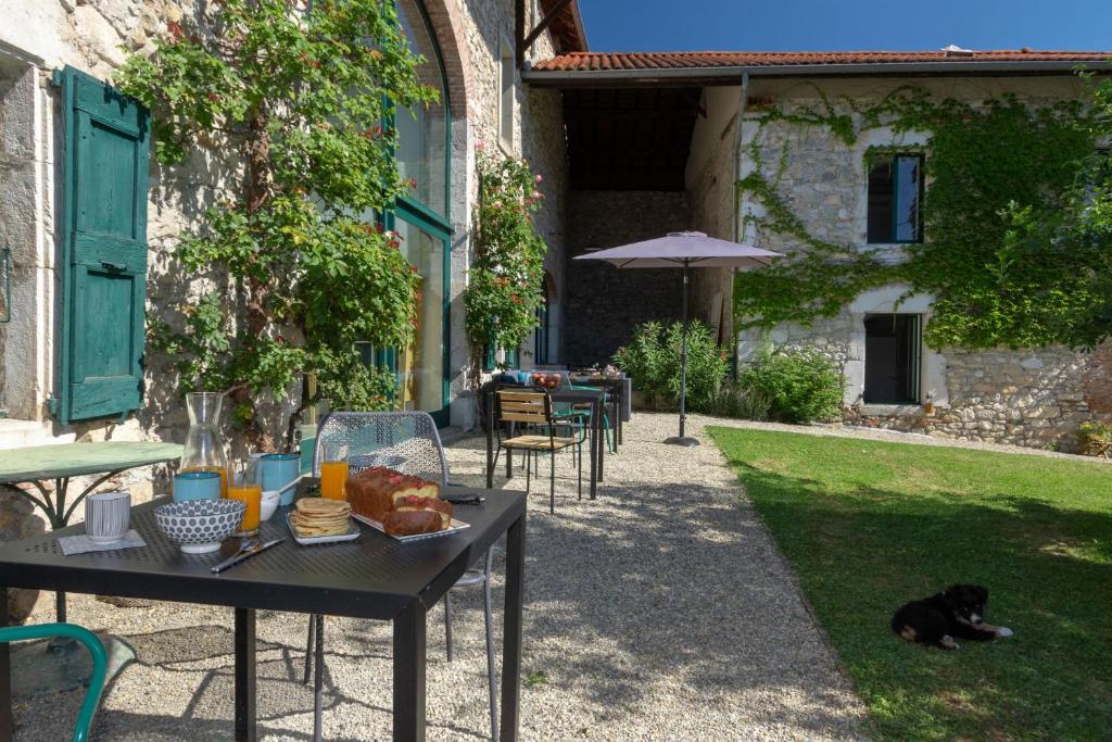 a black dog laying on the grass next to a table at L'Abelli d'Estelle in Le Touvet