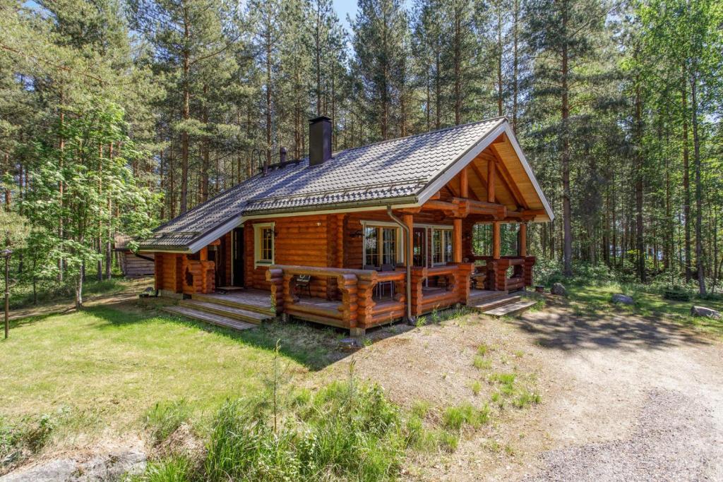 a log cabin in the woods with a porch at Nenäniemi in Tammijärvi