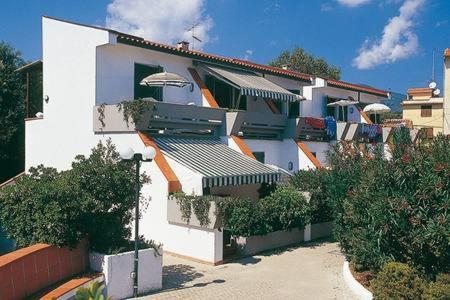 a white house with a lot of bushes and trees at Solaris18 in Marina di Campo